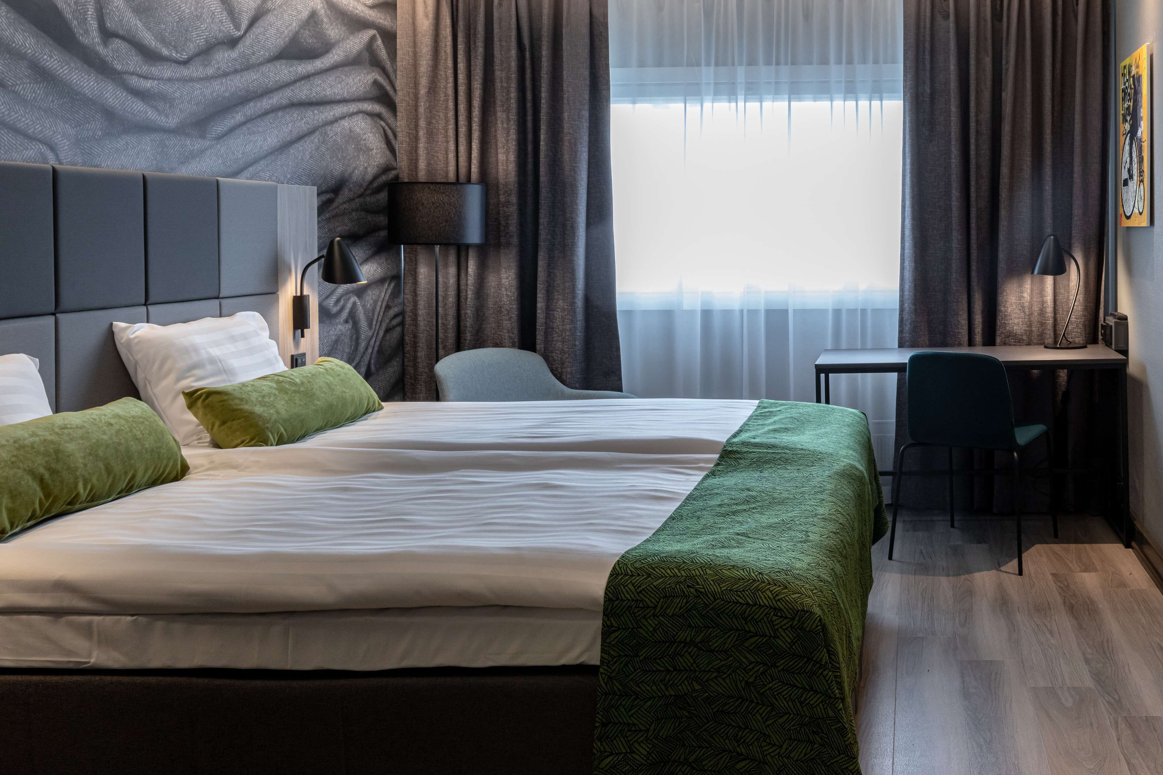 A modern hotel room with a large bed, a desk, and a chair.