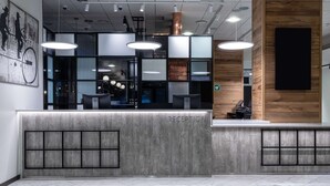 A reception area with a modern design, featuring a reception desk, a wooden accent wall, and a large artwork on the wall. - Scandic Pasila (Helsinki)