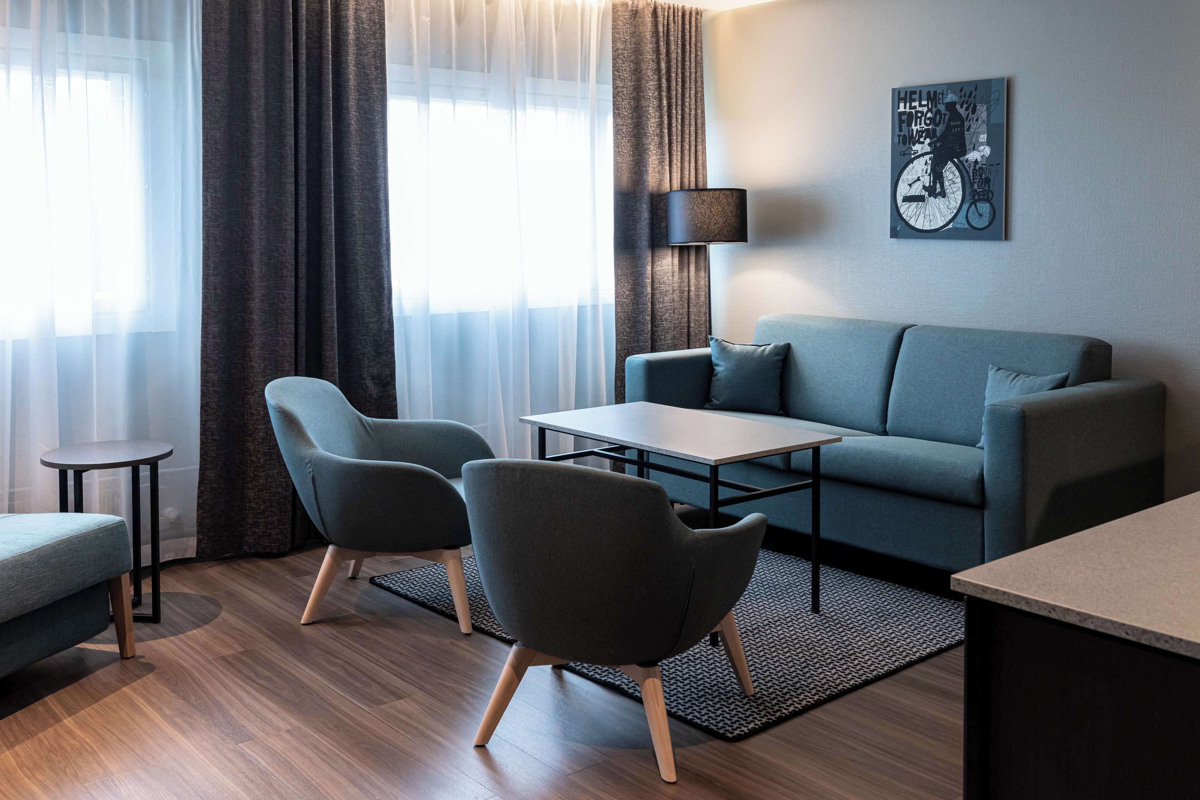 A modern living room with a sofa, two armchairs, a coffee table, and a lamp.