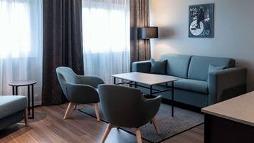 A modern living room with a sofa, two armchairs, a coffee table, and a lamp.
