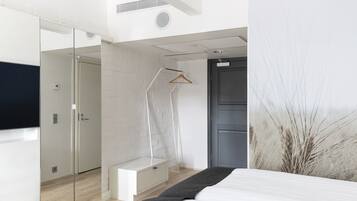 Un dormitorio moderno con cama, vestidor, ducha y un espejo grande.