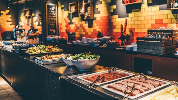 Un bufé con diversos alimentos y una pared decorativa con diseño de ladrillo.