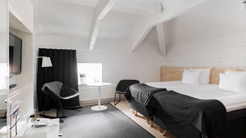 Moderni hotellihuone, jossa on suuri sänky, työpöytä tuolilla, televisio ja pieni pöytä.