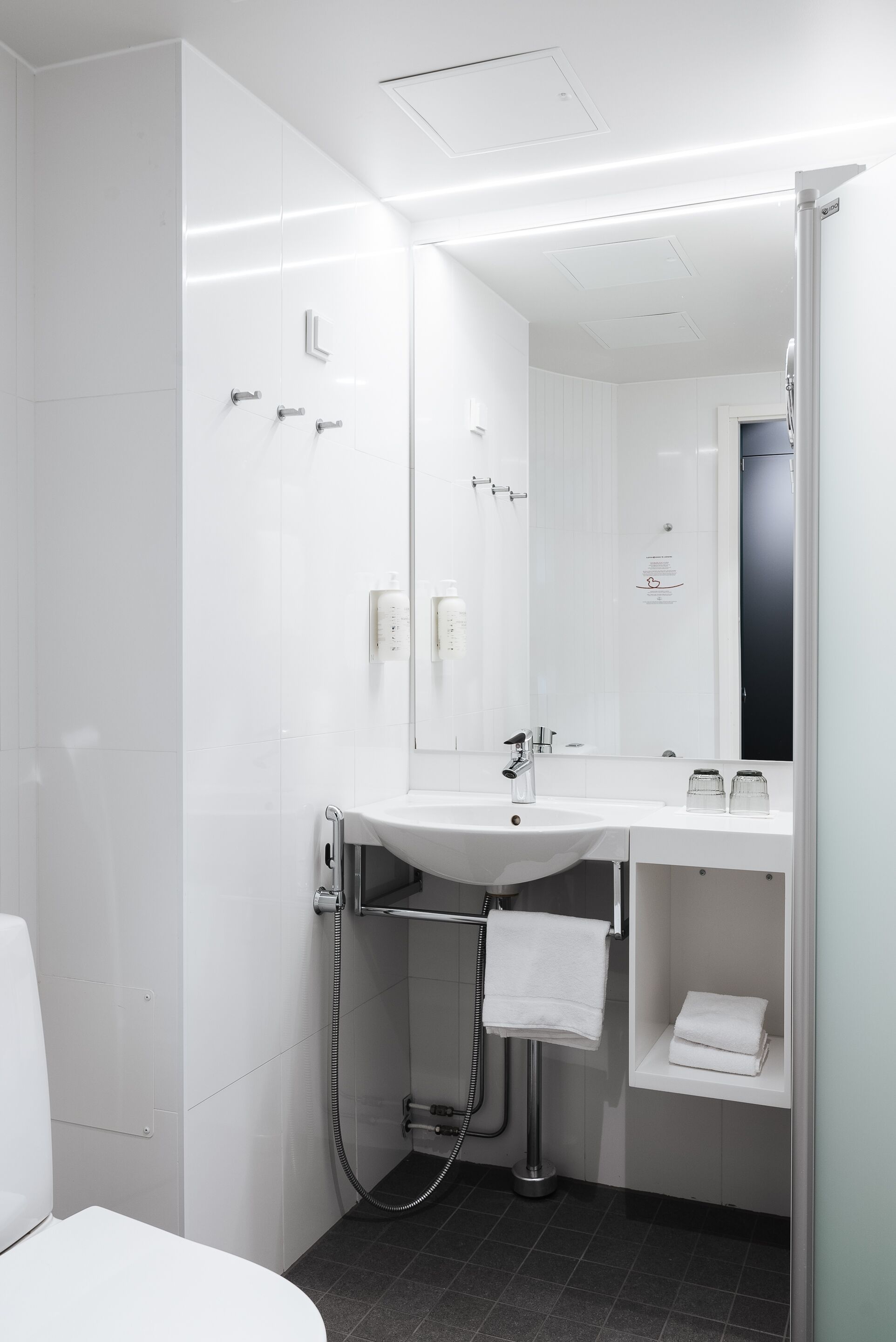 A modern bathroom with a white sink, mirror, and towel rack.