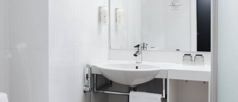 A modern bathroom with a white sink, mirror, and towel rack.