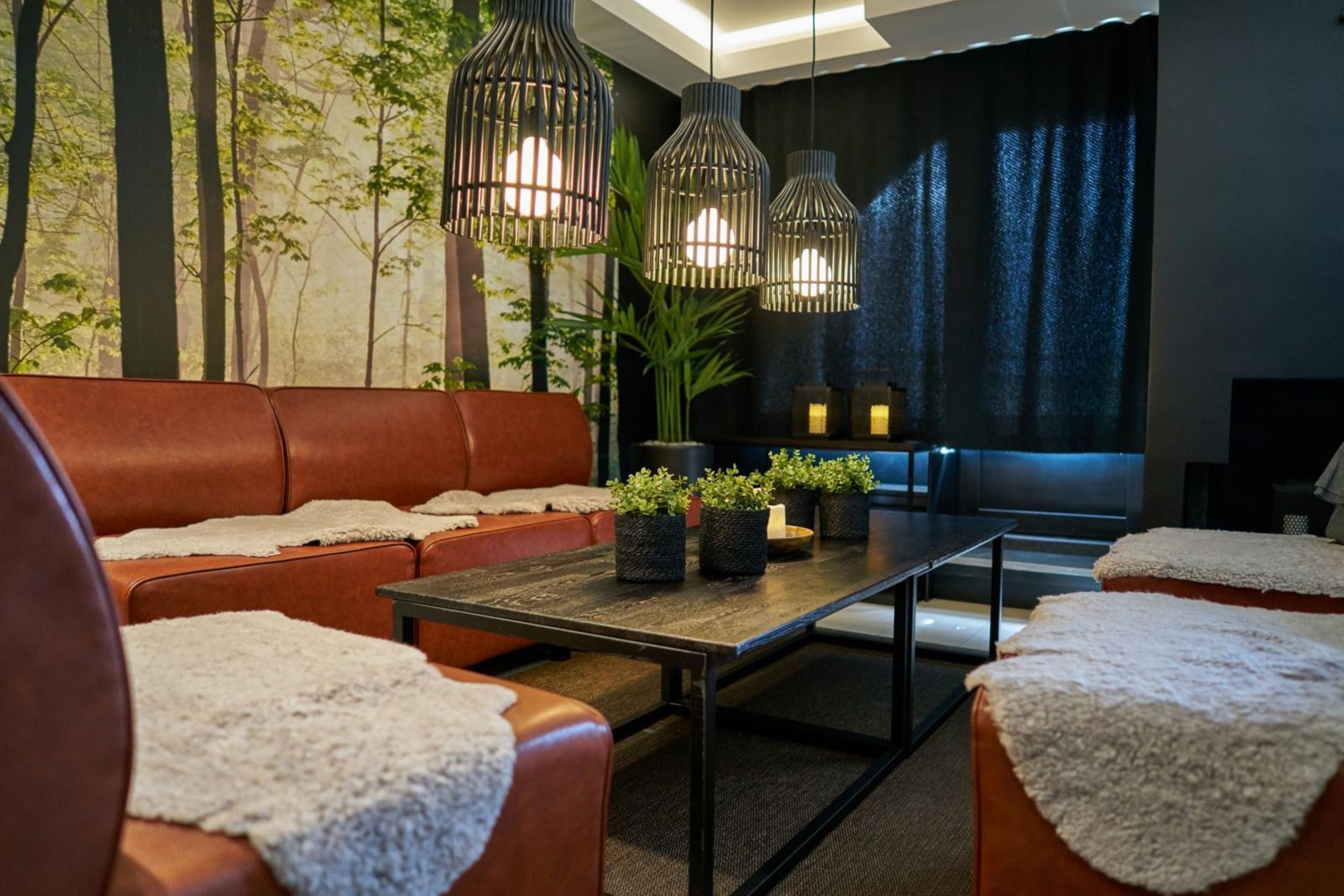 Een moderne woonkamer met een leren bank, een salontafel en hangende pendelverlichting.
