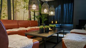 Een moderne woonkamer met een leren bank, een salontafel en hangende pendelverlichting.