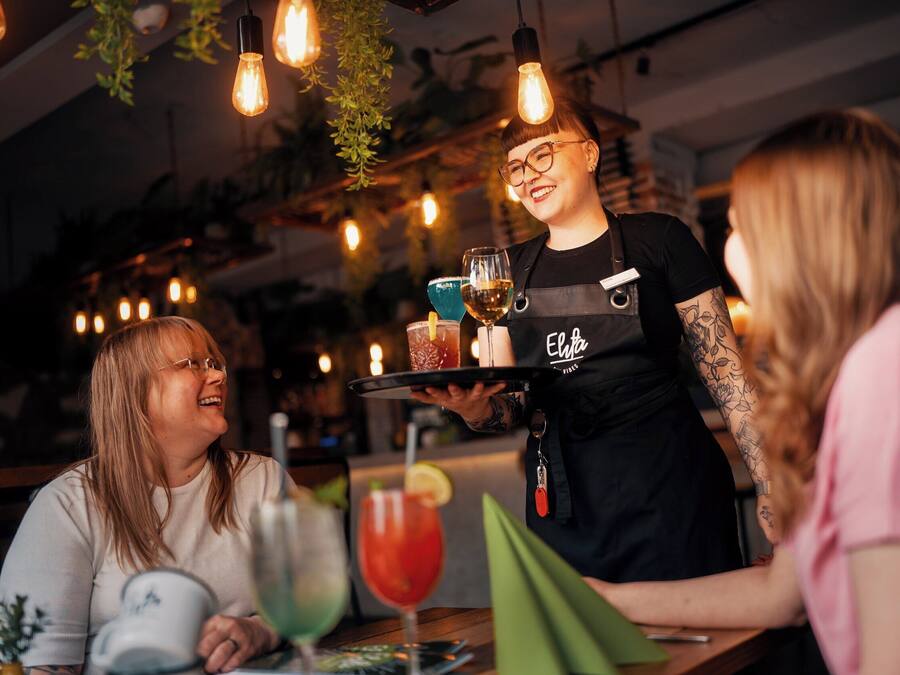 A bar setting with a bartender serving drinks to customers.