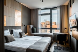 Relax in a spacious room with a large bed, seating area, and desk, offering a city view.