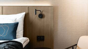 A modern hotel room with a neatly made bed, a small round table, and a chair.