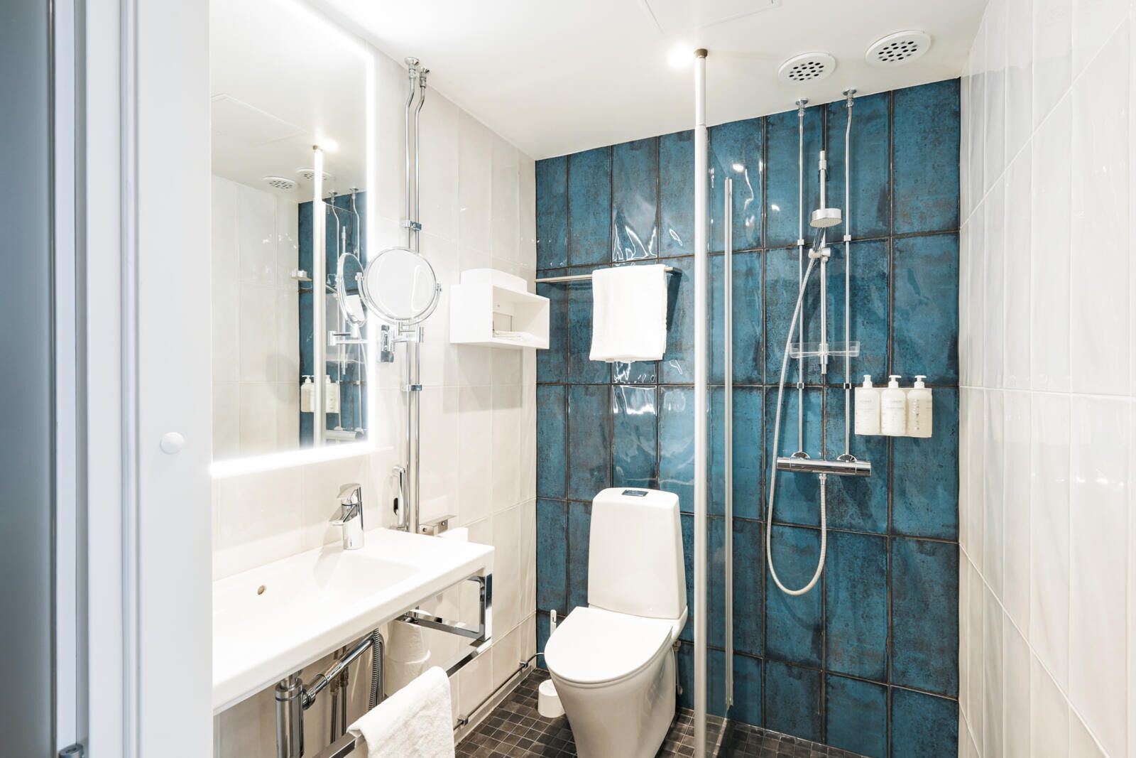 Ein modernes Badezimmer mit Waschbecken, Toilette und Dusche, alles in Weiß.