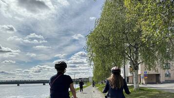 A paved path alongside a body of water with cyclists and a dog.