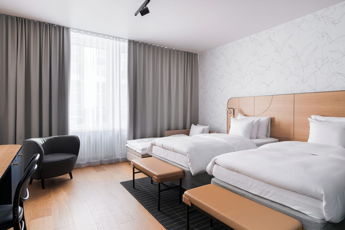 Habitación de hotel con dos camas, un escritorio y una silla.