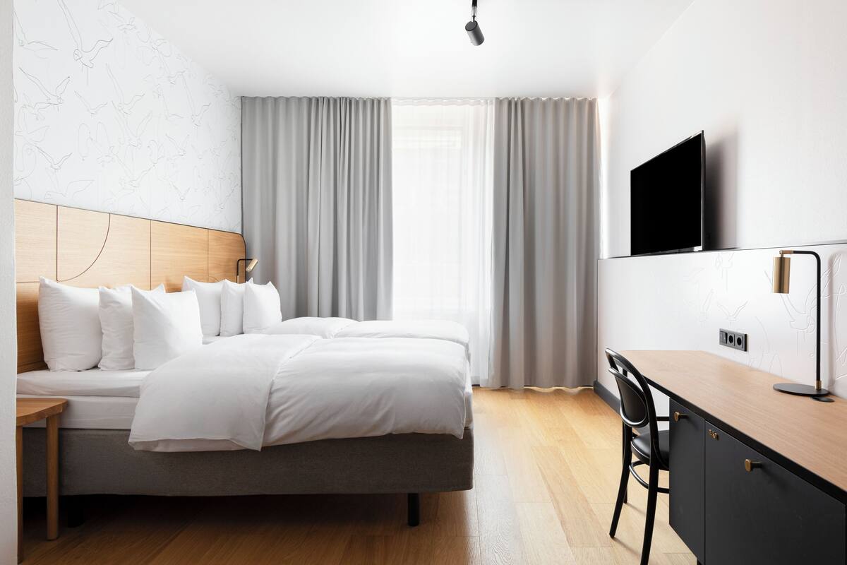 Una habitación de hotel moderna con cama, escritorio y televisión.