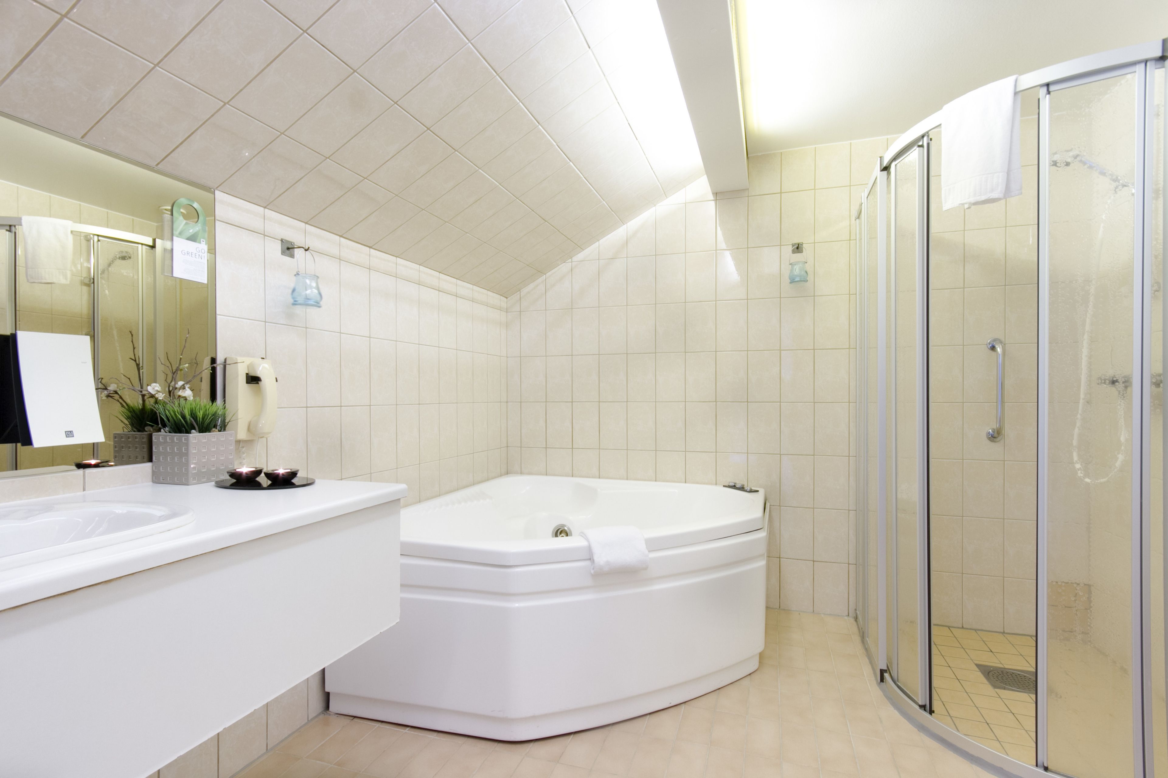 A modern bathroom with a large bathtub, a separate shower area, and a vanity with a mirror.