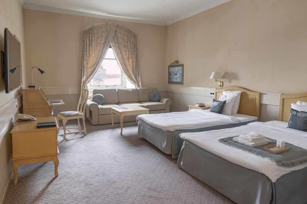 A hotel room with two beds, a sofa, a desk, and a chair.
