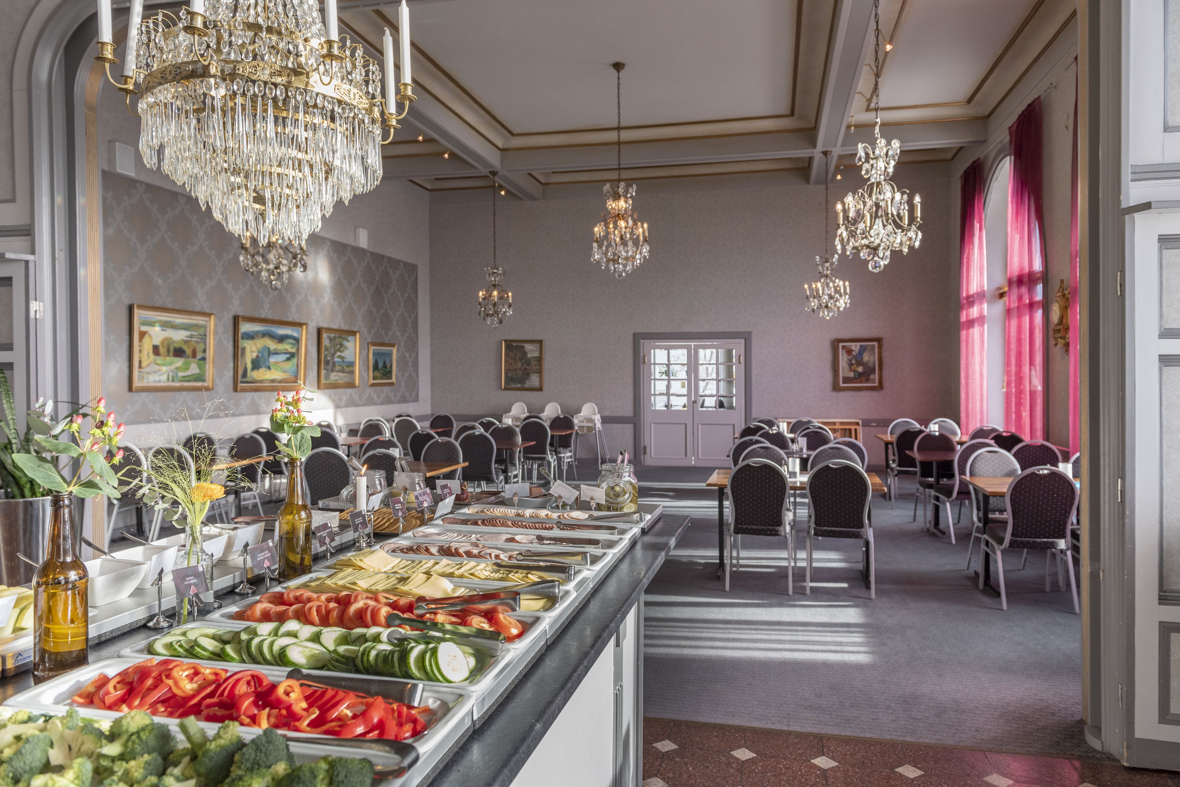 Zona de bufé con diversas opciones de comida, candelabros y mesas de comedor.