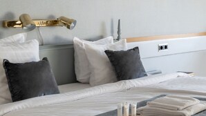 A neatly made bed with a grey blanket, white pillows, and a small wooden tray with toiletries. - First Hotel Statt Örnsköldsvik (Ornskoldsvik)