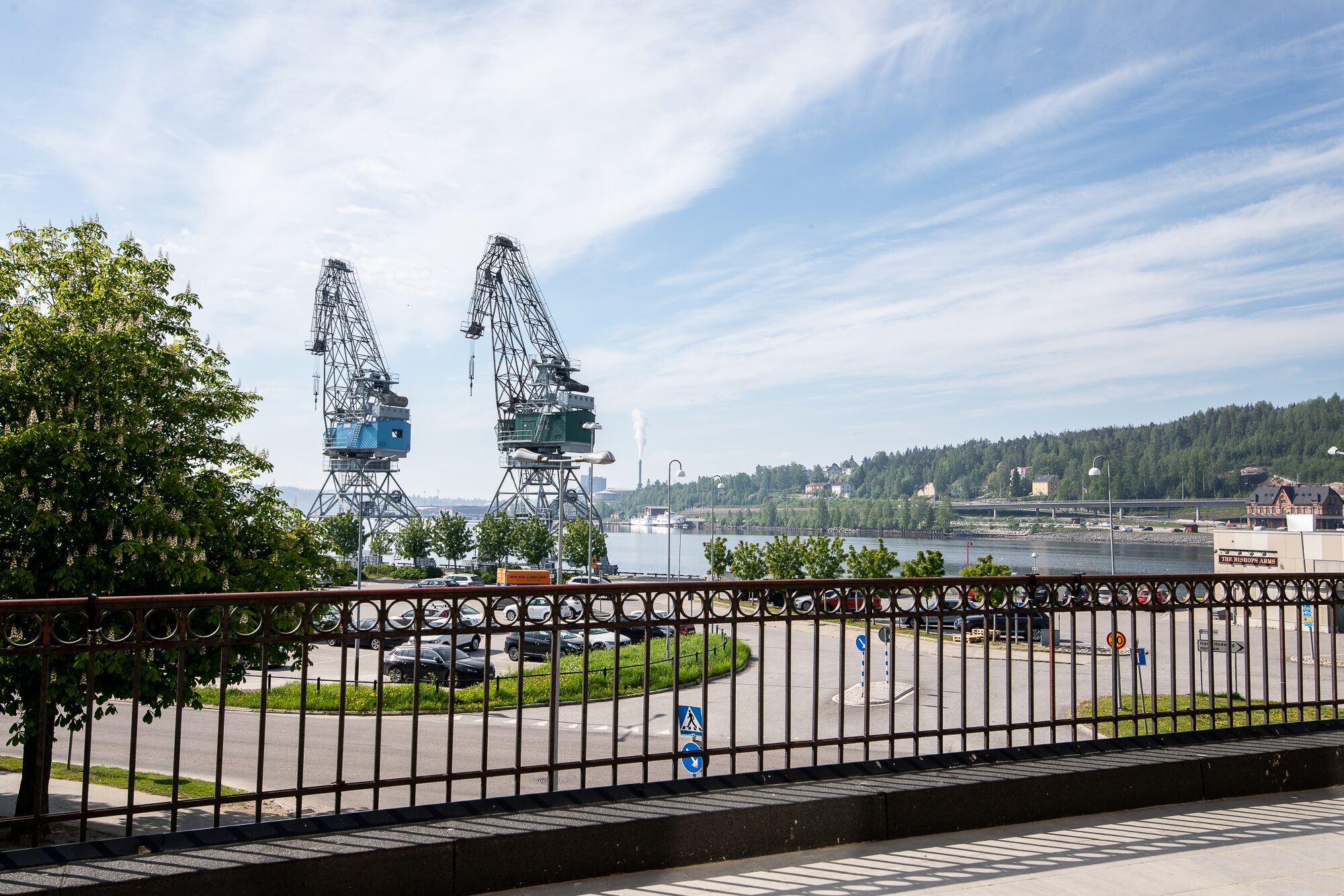 A view of a river with industrial cranes and a bridge in the background.