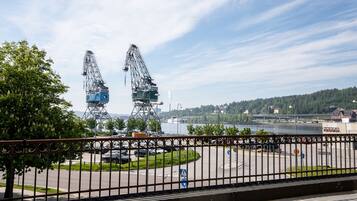 A view of a river with industrial cranes and a bridge in the background.