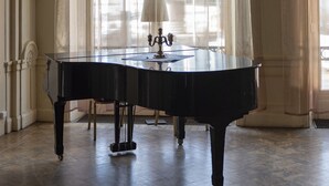 A grand piano in a spacious room with large arched windows and a chandelier. - First Hotel Statt Örnsköldsvik (Ornskoldsvik)