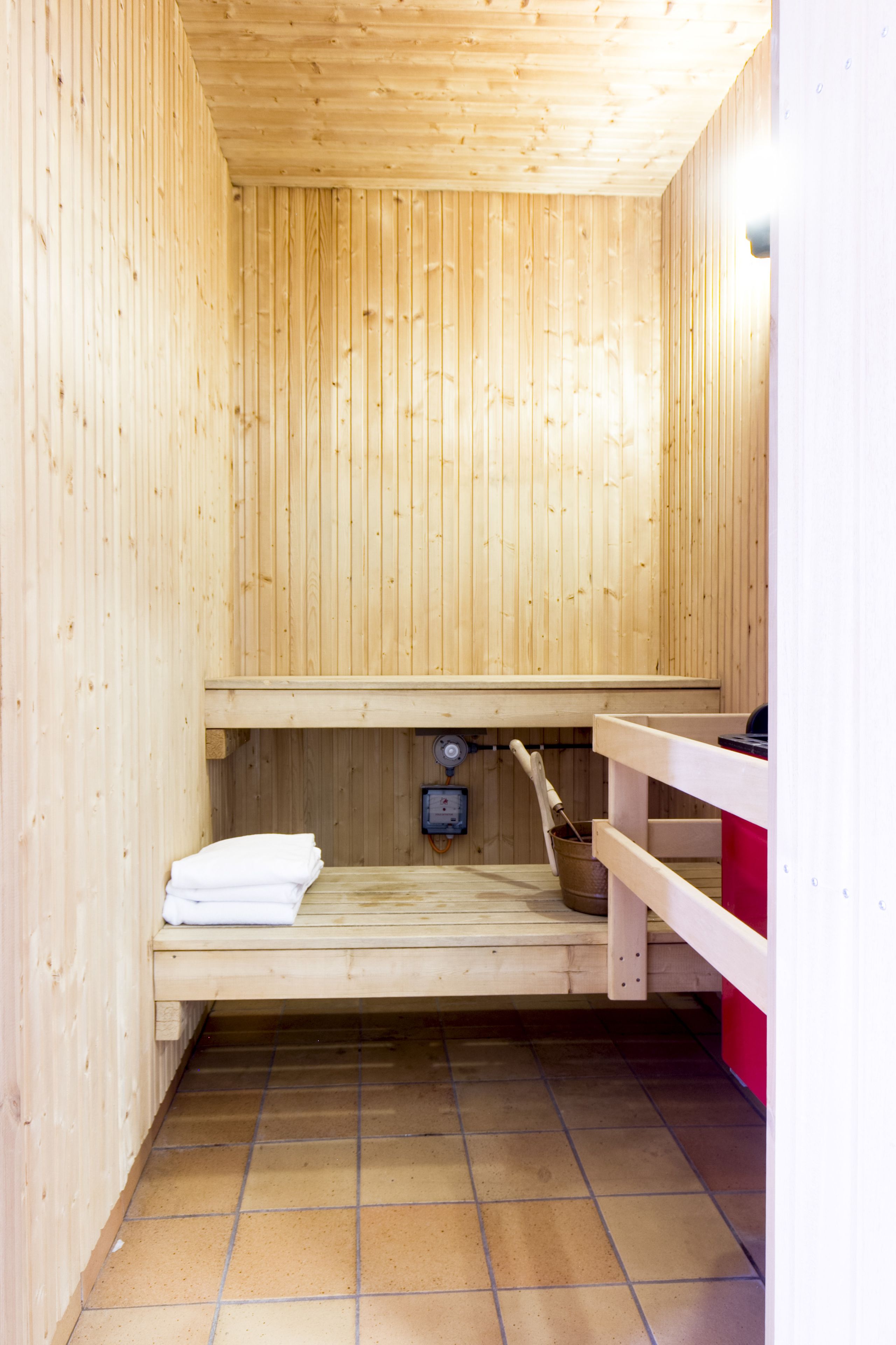 Una sauna de madera con un banco, una toalla y un cubo.