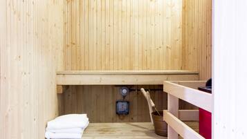 Una sauna de madera con un banco, una toalla y un cubo.