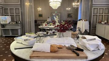 A dining area with a round table set for a meal, featuring bread, utensils, and a vase with flowers.