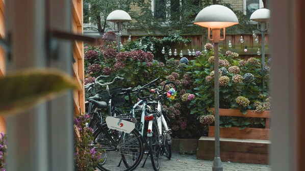 Bicicletas estacionadas en un jardín con valla de madera y un banco.