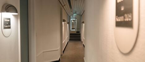 A hotel hallway with a carpeted floor, walls with light fixtures, and a sign indicating Room 217.