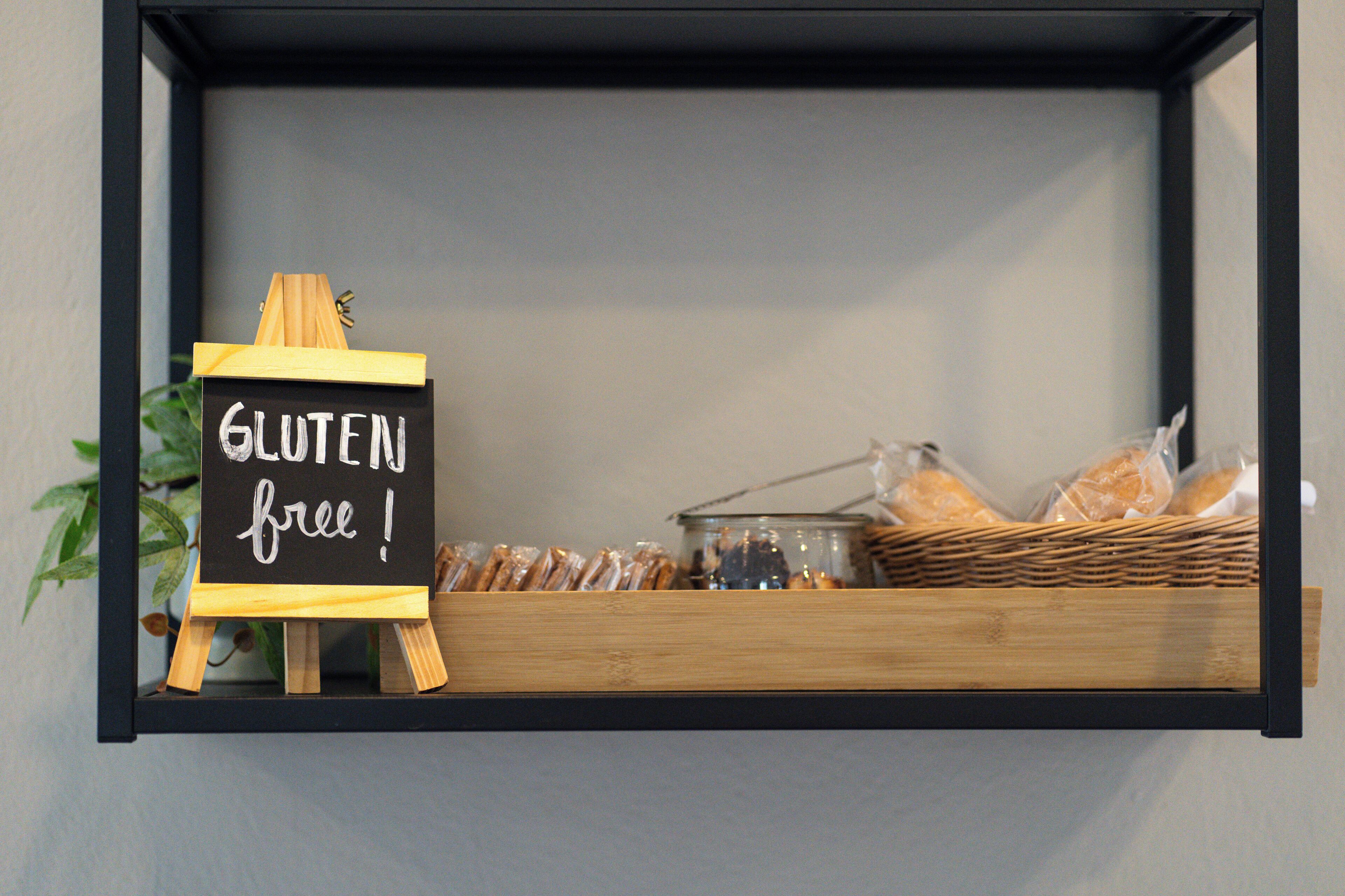 Letrero que indica opciones sin gluten en una repadera con pan y pasteles.