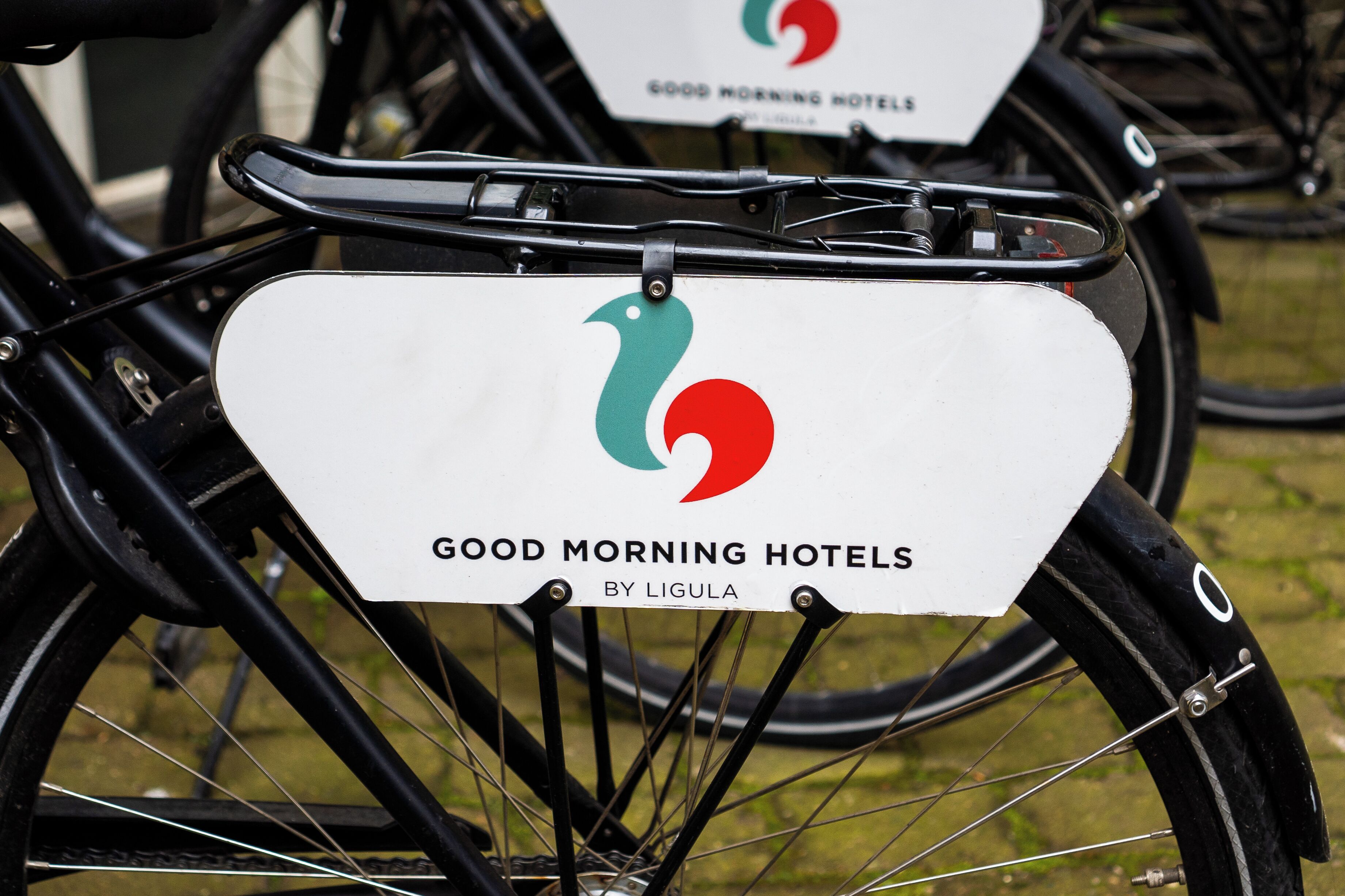 Een fiets met een wit bord waarop staat 'GOOD MORNING HOTELS BY LIGULA'.