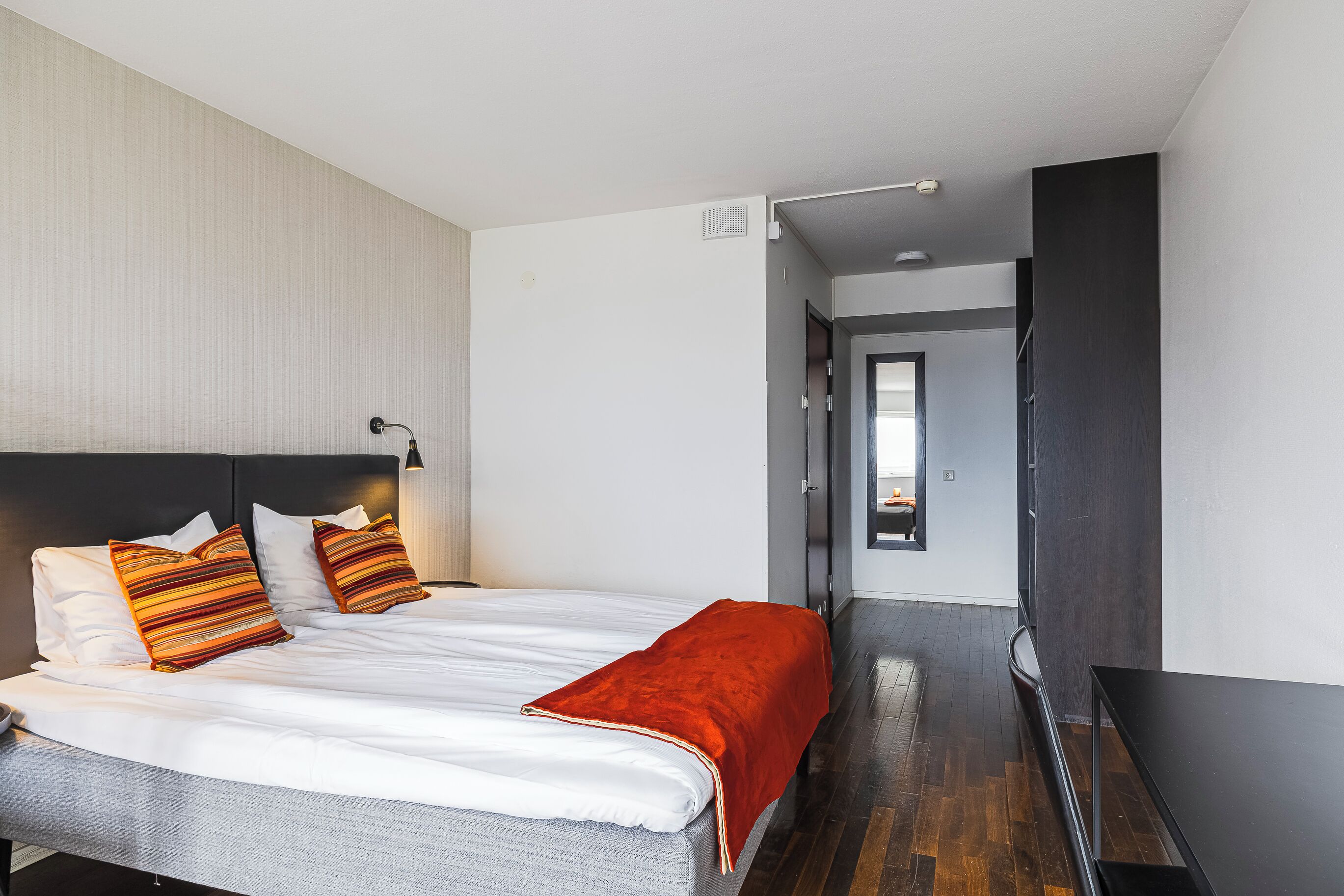 Una habitación de hotel moderna con una cama grande, un escritorio y vistas al pasillo.
