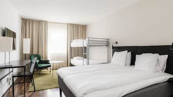 Ein Hotelzimmer mit einem Etagenbett, einem Schreibtisch mit Stuhl, einem kleinen runden Tisch und einem grünen Sessel.