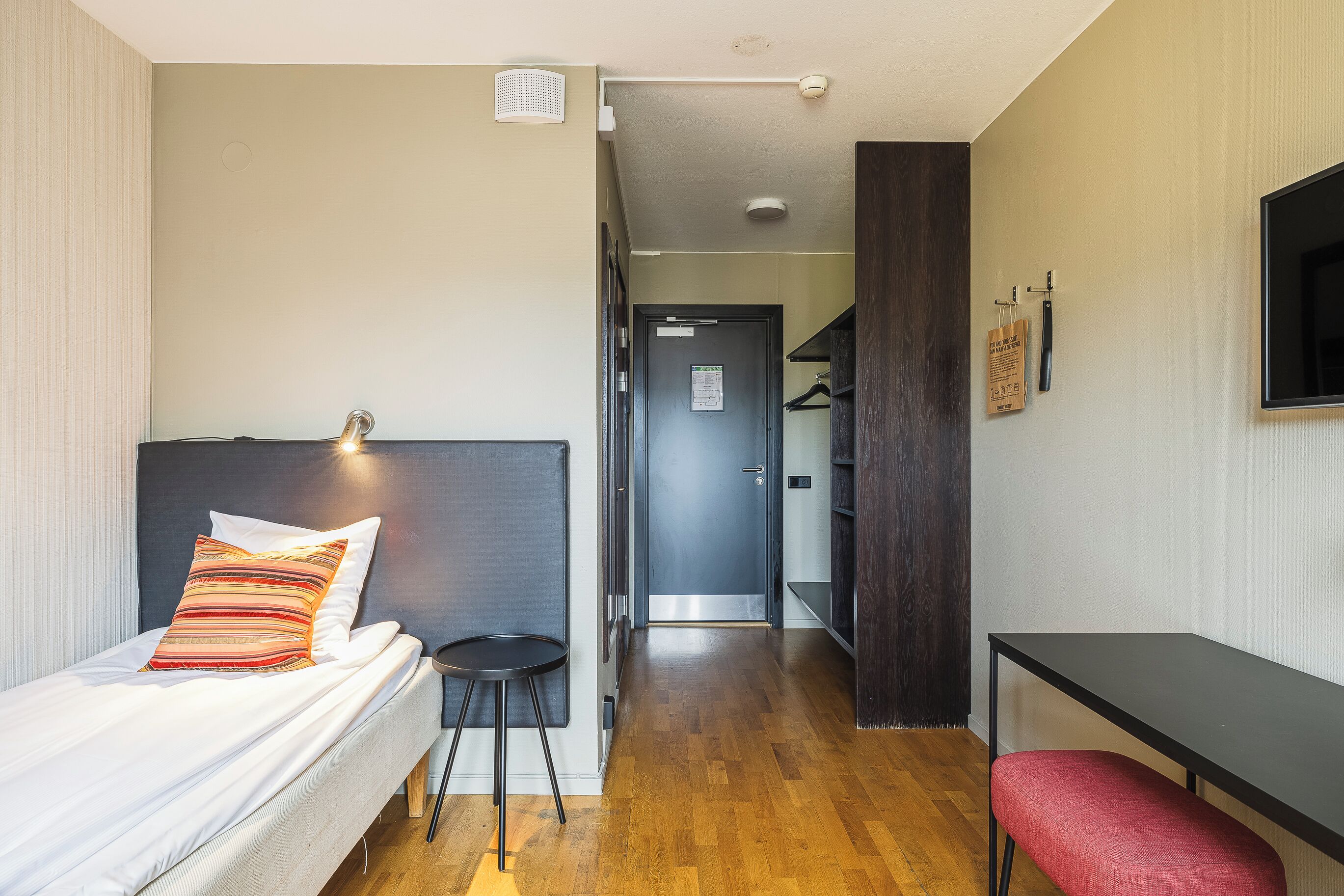 A hotel room with a bed, a desk, a chair, and a TV.