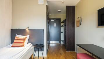 Ett hotellrum med en säng, ett skrivbord, en stol och en tv.