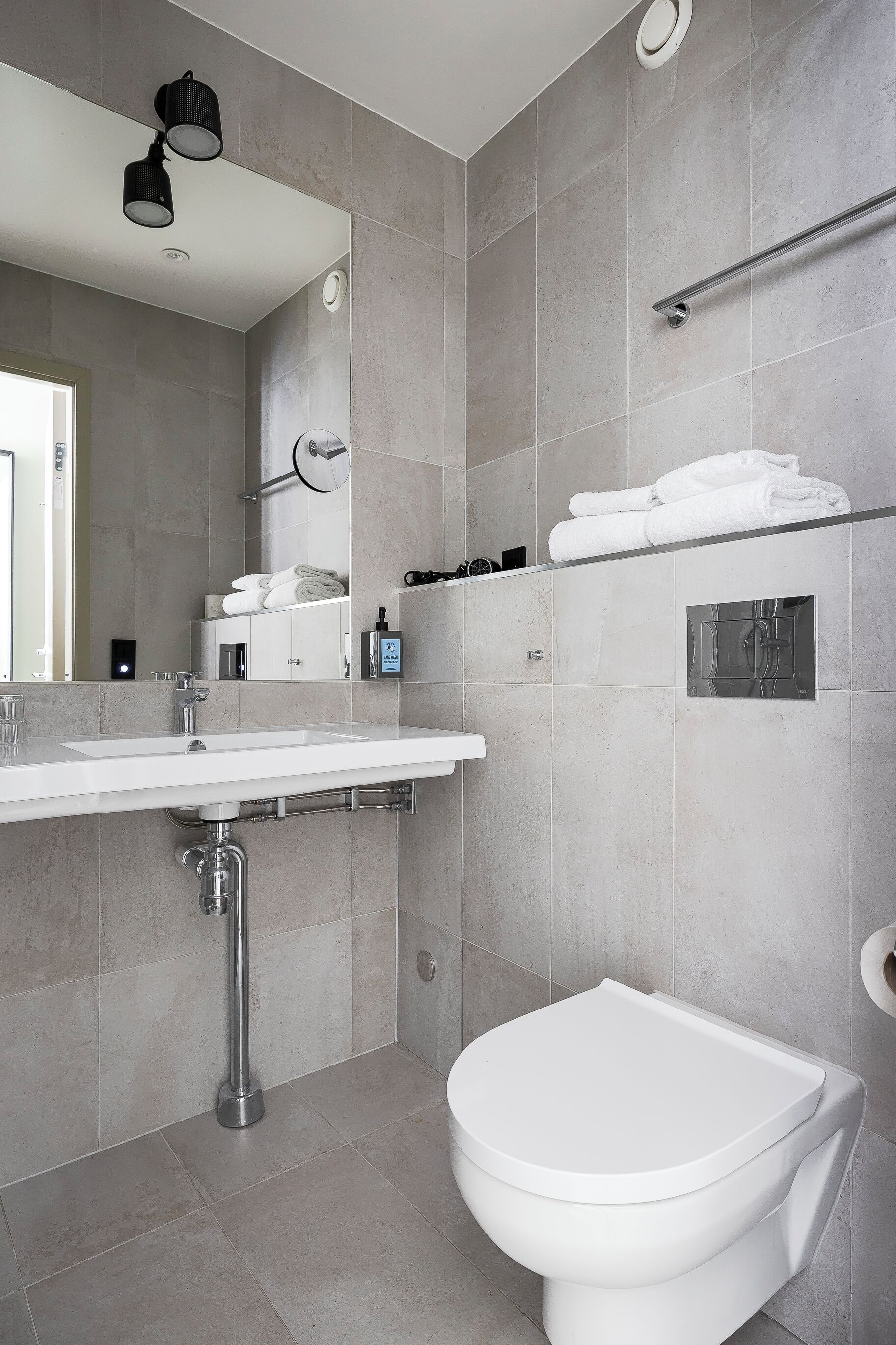 Un baño moderno con un lavabo blanco, un inodoro y un perchero para toallas.