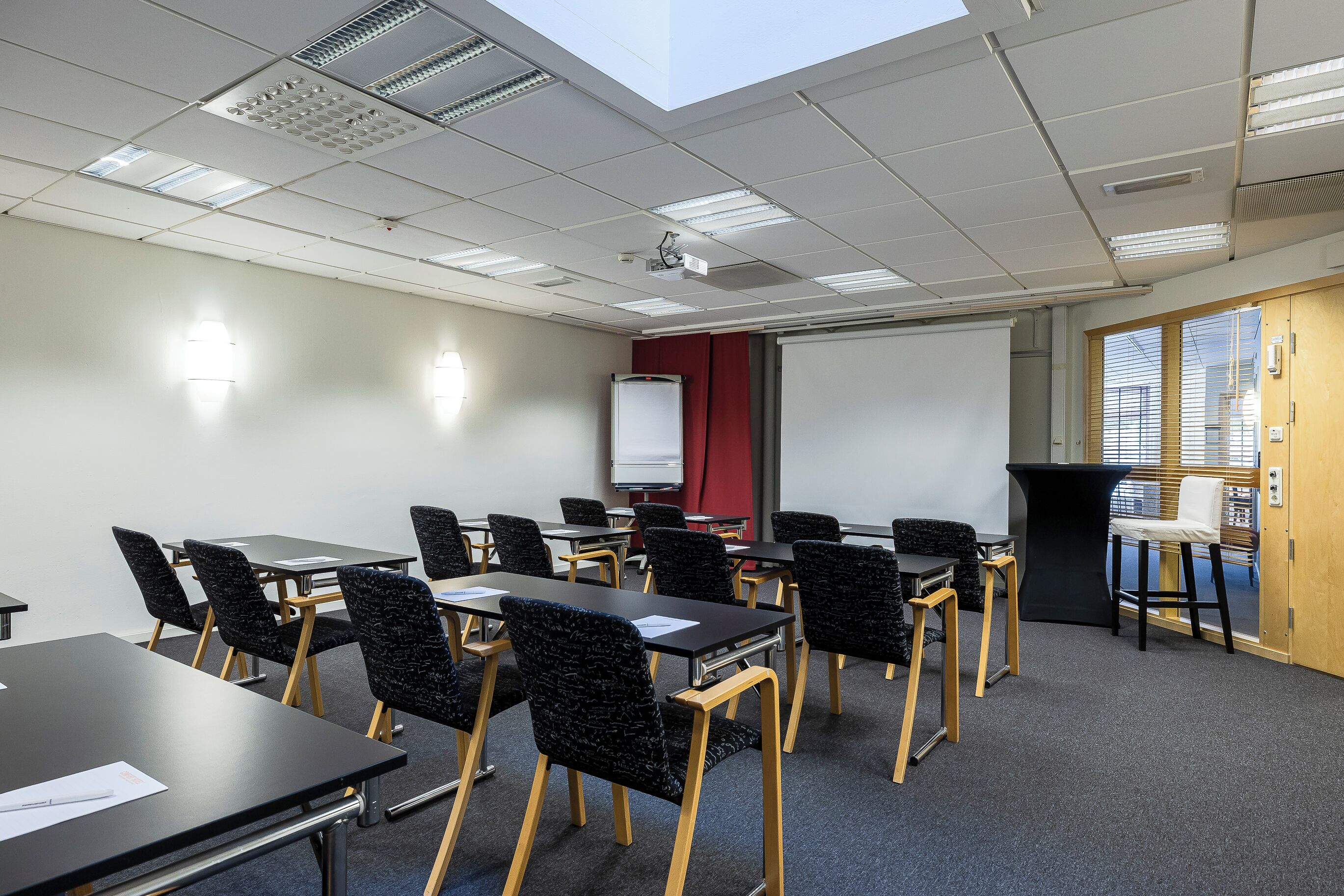 Una sala de conferencias con mesas y sillas, una pizarra y un proyector.