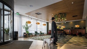 En rymlig entréhall med ett träpanelat tak, ett mönstrat golv och en receptionsdel med en disk och sittplatser.