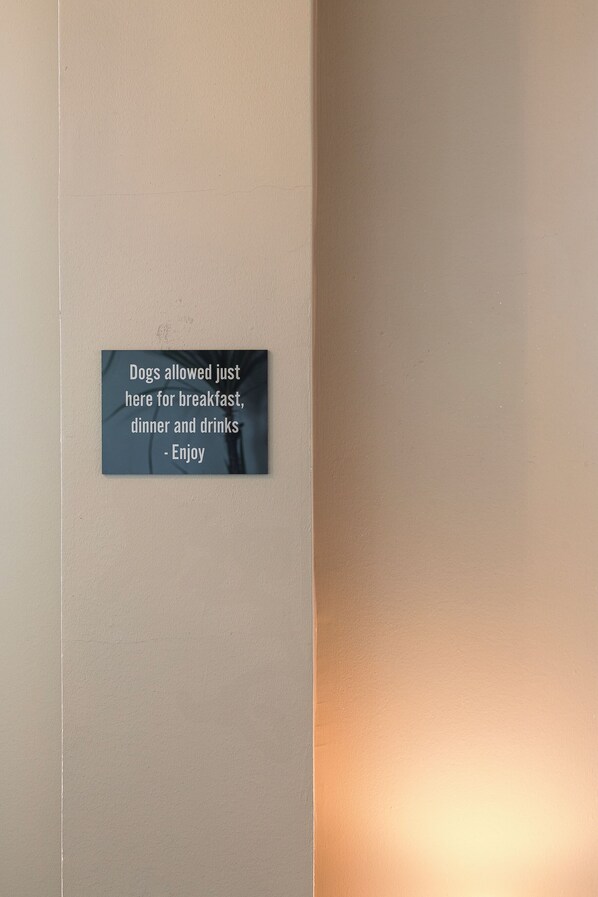 Pared con un cartel que indica que se permiten perros para el desayuno, la cena y bebidas.