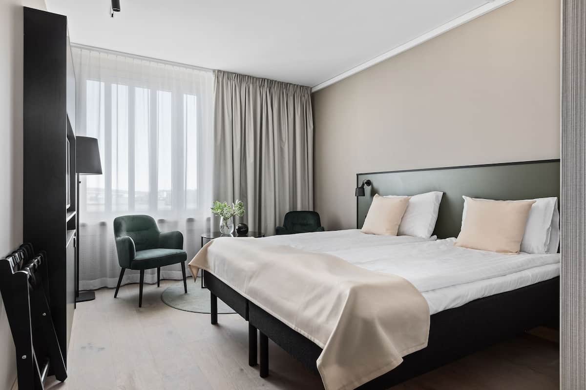 Une chambre d’hôtel moderne, dotée d’un grand lit, d’une chaise, d’un bureau et d’un radiateur.