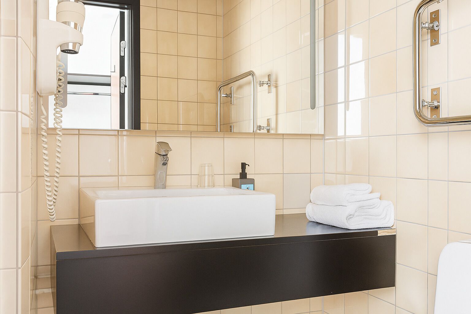 A modern bathroom with a large sink, a mirror, a towel rack, and a telephone.