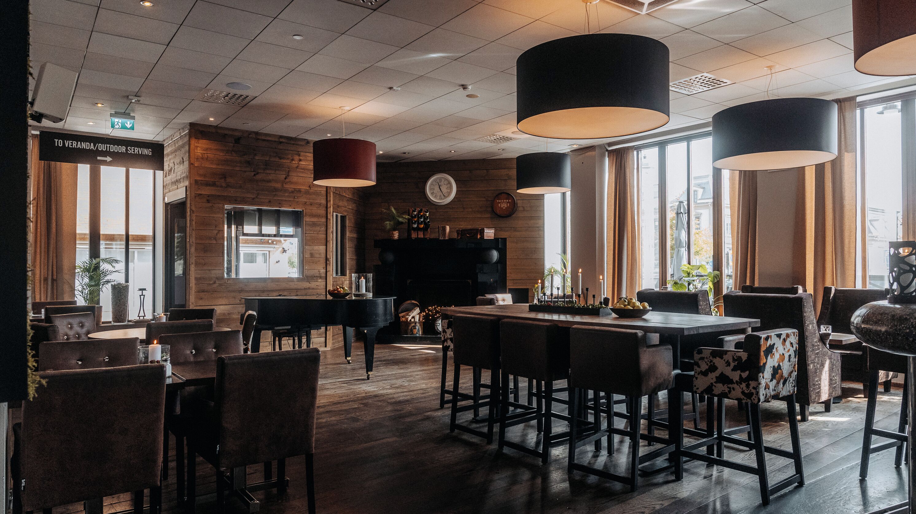 Un restaurante con barra, paredes de madera y ventanas amplias.