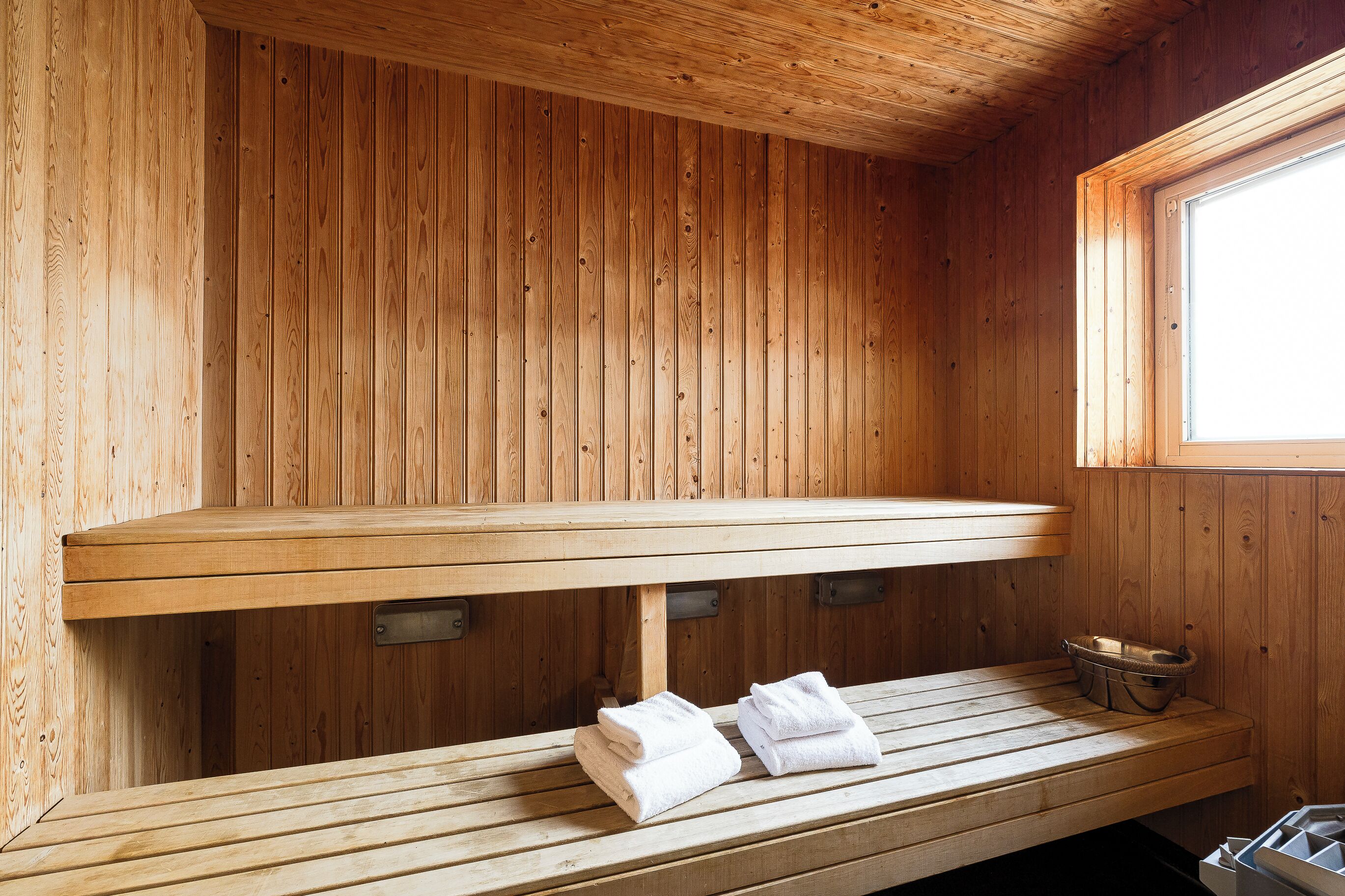 A wooden sauna with benches and towels.