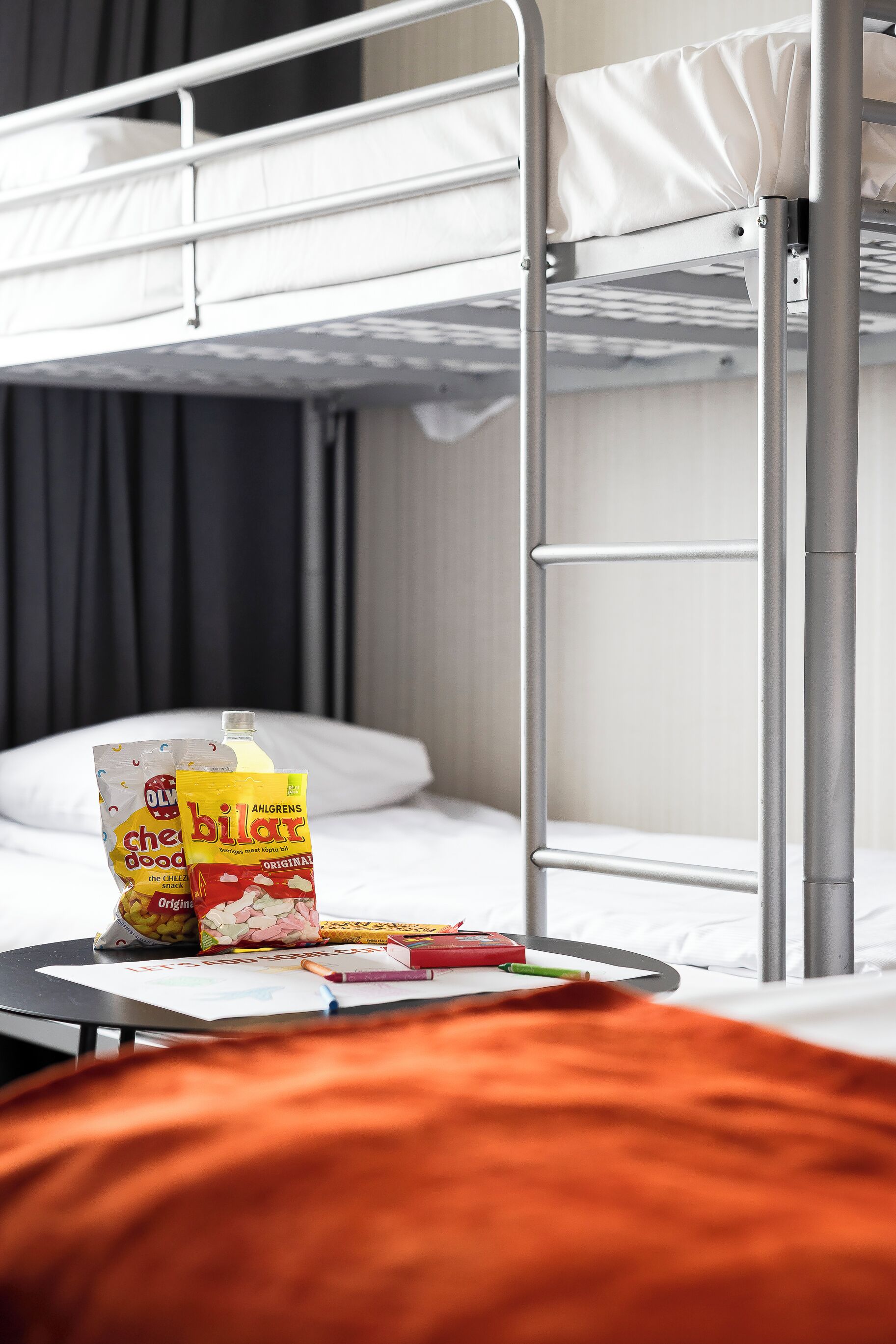 A bunk bed with a table in front, containing snacks and a bottle.