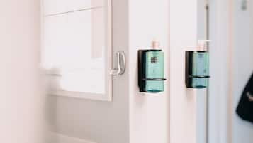 A bathroom with a white sink, a mirror, and two green bottles on the wall.