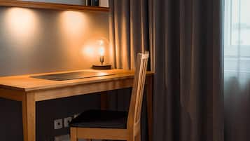 Un escritorio de madera con una lámpara, una silla y un cuadro en la pared.