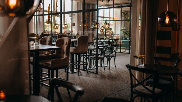 An interior with tables and chairs, large windows, and hanging light fixtures. - Sunlight Hotel Conference and Spa (Nykoping)