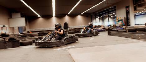 A go-kart track with two go-karts and riders in helmets.