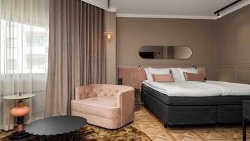 Una camera d'albergo moderna con un letto, una sedia, un tavolino e un'ampia finestra con tende.